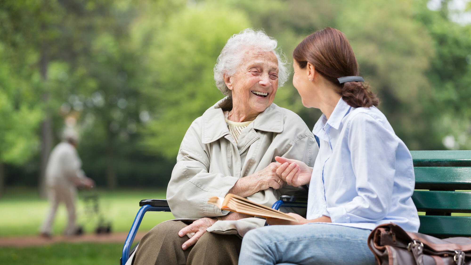 Une dame agée et une aide-soignante discutent sur un banc