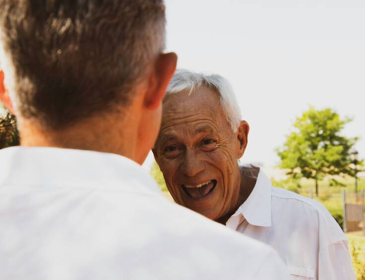 Homme âgé souriant à une personne de dos